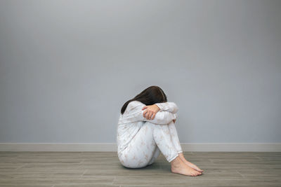 Low section of woman sitting on hardwood floor