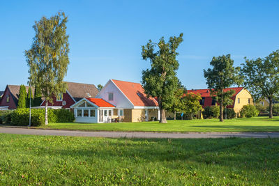 Houses on field by trees against sky