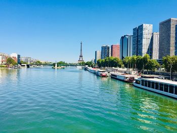 Scenic view of river and buildings against clear blue sky