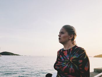 Young woman looking at sea against clear sky
