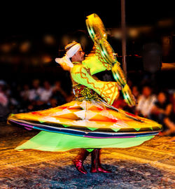 Midsection of woman with umbrella during night