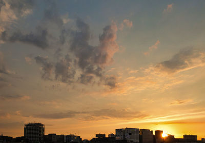 Buildings against dramatic sky during sunset
