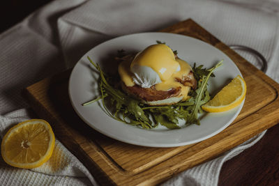 Eggs benedict and poached hollandaise sauce with arugula and lemon. delicious food for breakfast. 