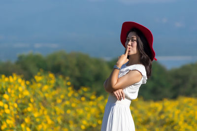 Woman standing on land against yellow flowering plants