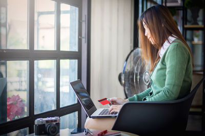 Woman using mobile phone while sitting on table