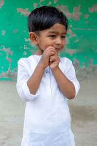 Cute boy standing against wall