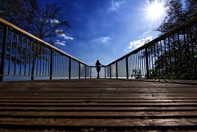 Low angle view of man on footbridge against sky