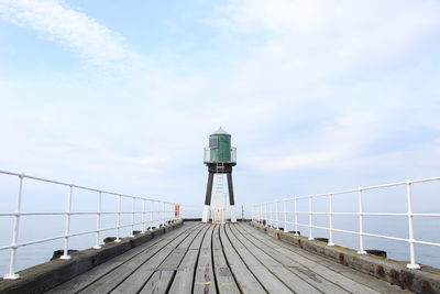 Lighthouse by sea against sky