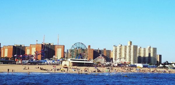 Modern buildings by sea against clear sky