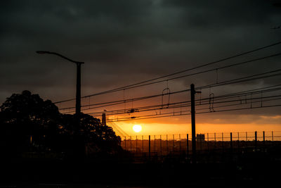 Silhouette street against dramatic sky during sunset