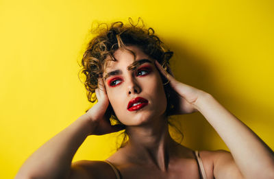 Close-up of young woman looking away against yellow background