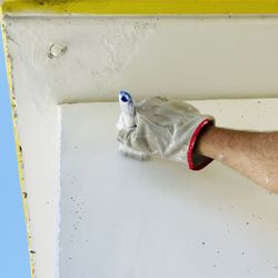 Hand of man holding painting a white wall