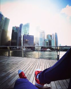 Low section of woman with cityscape against sky