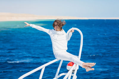 Woman relaxing on the nose of the yacht at a sunny summer day at sea