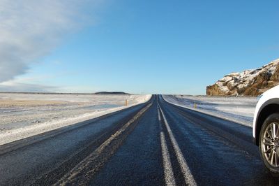 Country road against sky during winter