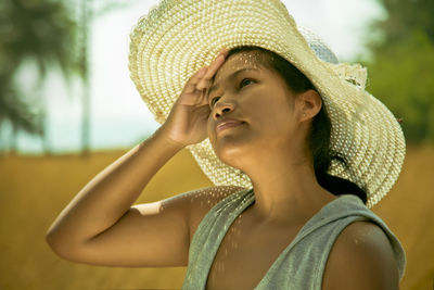 Close-up of woman wearing sun hat while looking up on sunny day