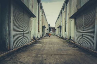 Tilt shift image of man standing in alley amidst buildings in city