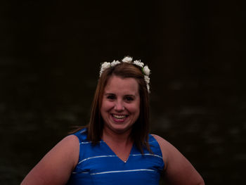 Portrait of smiling young woman against black background