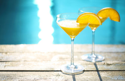 Wine glass on table by swimming pool