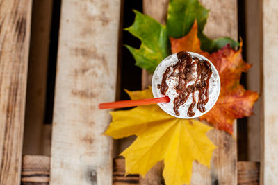 Autumn composition still life. cup of coffee latte with cocktail straw and autumn colored leaves on