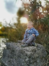 Cute boy sitting on rock