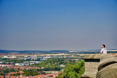 People looking at city against clear blue sky