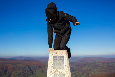 Man standing on mountain against clear blue sky