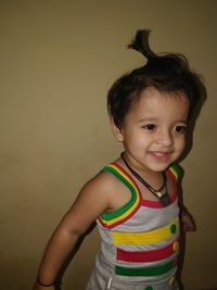 Portrait of smiling girl standing against wall