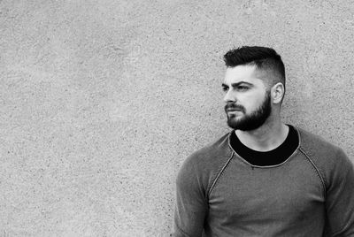 Portrait of young man standing against wall