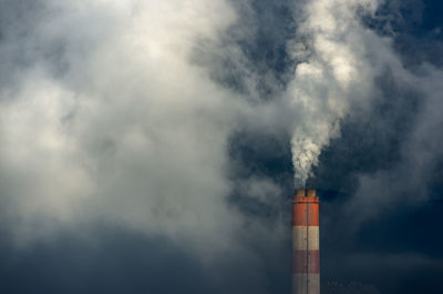 Low angle view of smoke emitting from chimney against sky