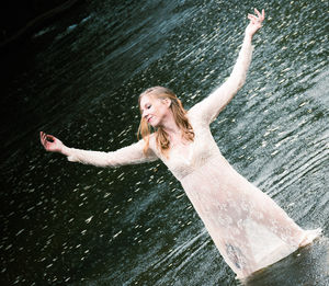 Full length of woman with arms outstretched in water