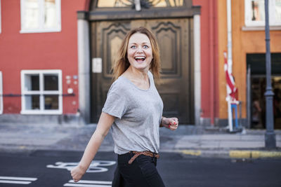 Portrait of smiling young woman standing in city