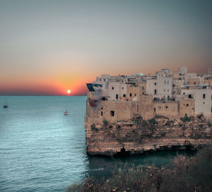 Scenic view of sea against buildings during sunset