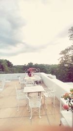 Chairs and table by trees against sky