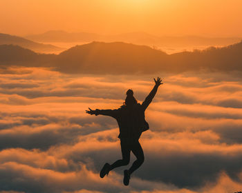 Low angle view of man jumping against sky during sunset
