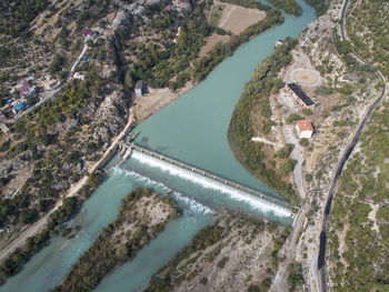 Dam at the mountain river and river island. aerial view