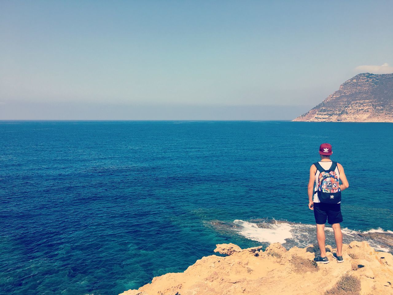 REAR VIEW OF MAN STANDING ON SHORE