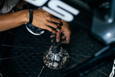 Cropped image of man repairing bicycle wheel