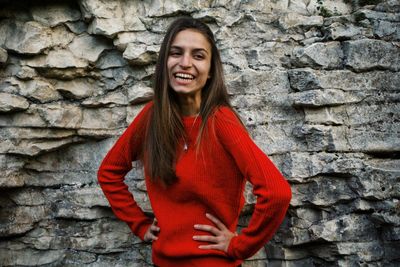 Cheerful young woman standing by wall