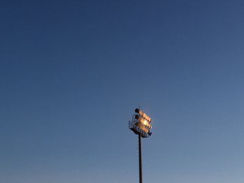 Low angle view of illuminated street light against clear blue sky