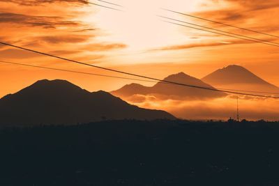 Scenic view of silhouette mountains against orange sky