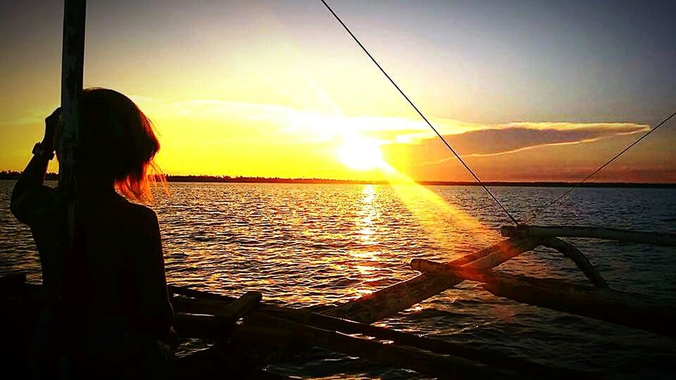 REAR VIEW OF SILHOUETTE WOMAN FISHING IN SEA