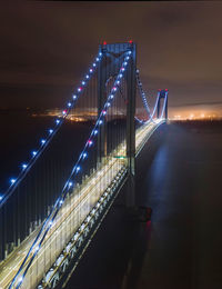 Illuminated bridge over river in city at night