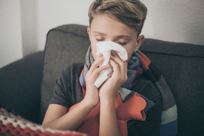 Boy suffering from cold while sitting on sofa