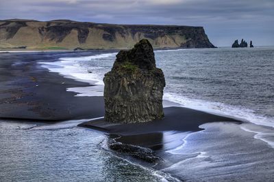 Rock formation on beach against sky
