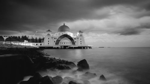 View of building by sea against cloudy sky