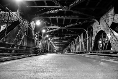 Illuminated bridge over road in city at night