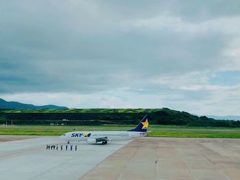 Airplane on airport runway against sky