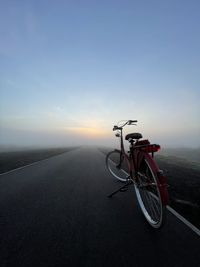 Bicycle on road against sky during sunset