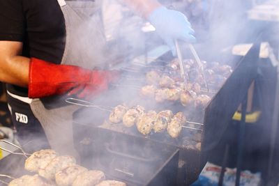 Close-up of man preparing food on barbecue grill